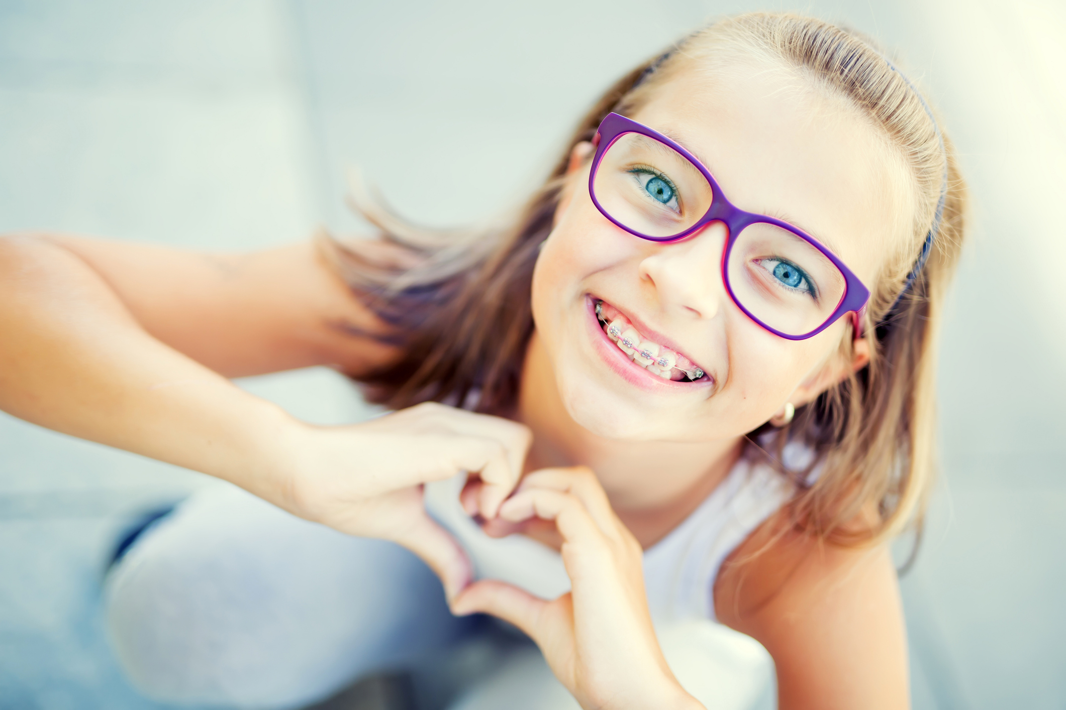 girl with braces making a heart